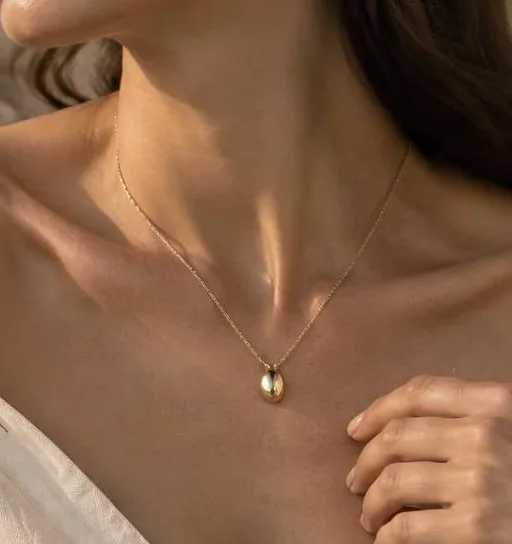 The Pebble Pendant resting against a natural neckline